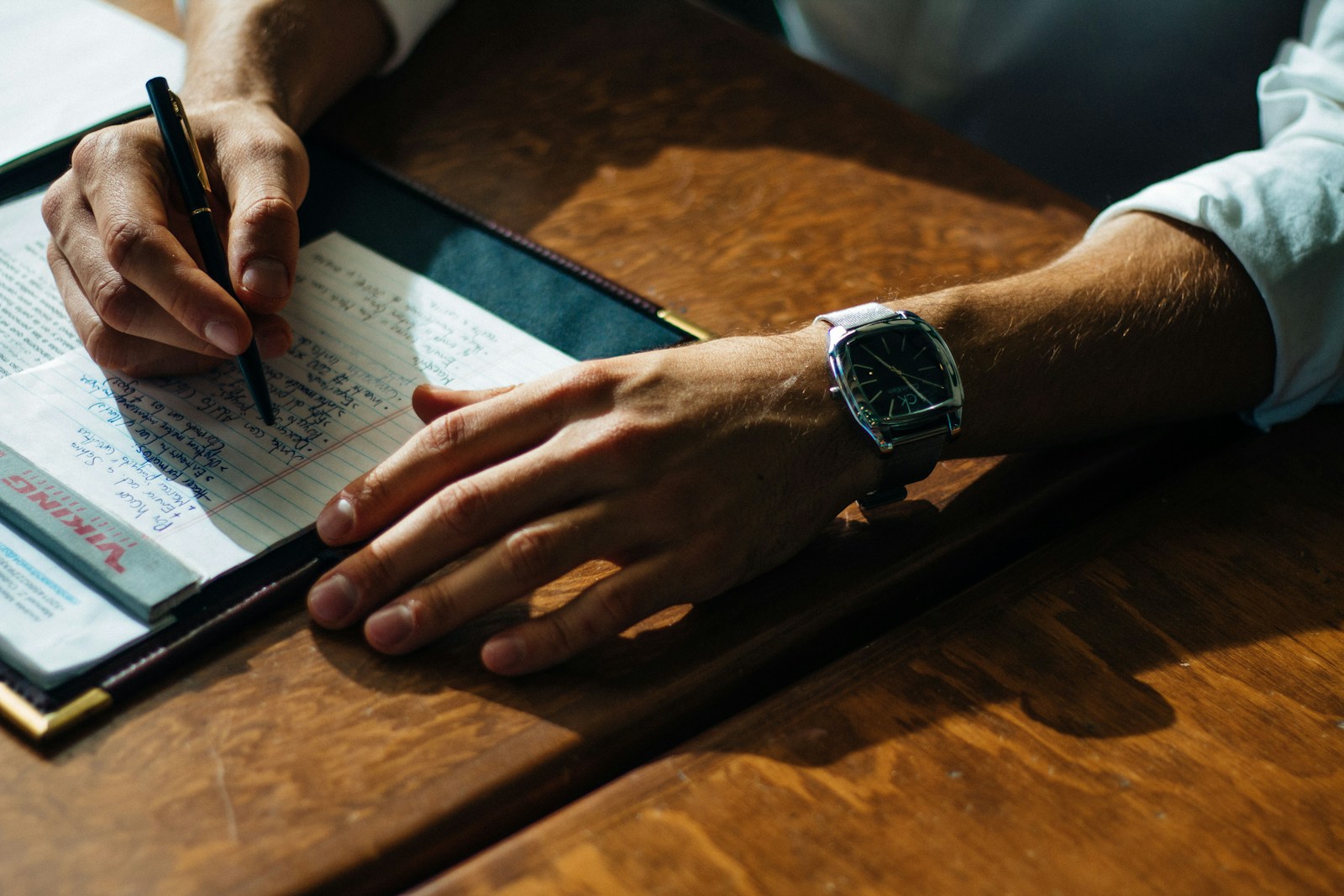 person writing on paper leaning on brown table professional liability