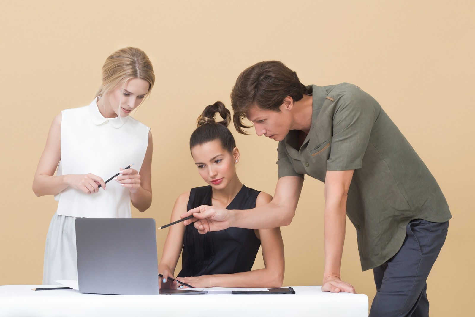 man teaching woman while pointing on gray laptop, business